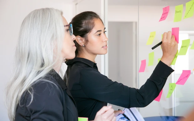confident-latin-businesswoman-writing-stickers-sharing-ideas-project-focused-grey-haired-female-manager-reading-notes-glass-wall confident-latin-businesswoman-writing-stickers-sharing-ideas-project-focused-grey-haired-female-manager-reading-notes-glass-wall